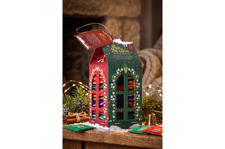 English Tea Shop Sip the Season house-shaped holiday tea advent calendar box filled with wrapped tea bags on a festive table.